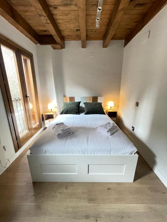 カンプロドンにあるApartamento dúplex en el corazón de Camprodon, La Roviraの大きな白いベッドと2つのランプのある寝室