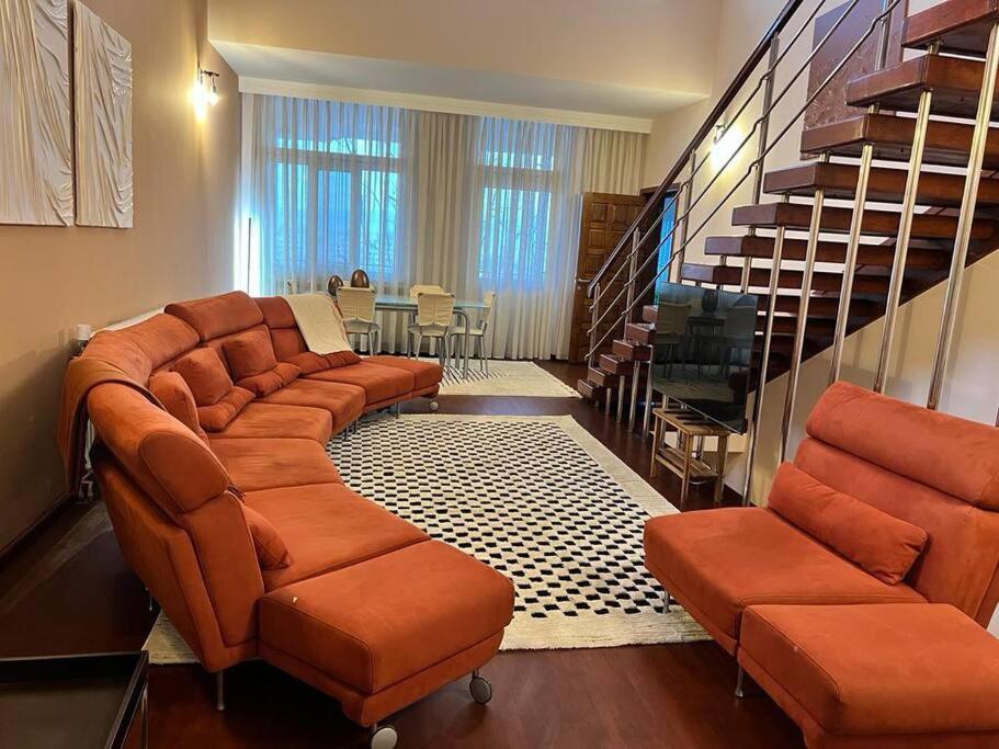 a living room with orange chairs and a staircase at Chic Deluxe Villa in Iaşi