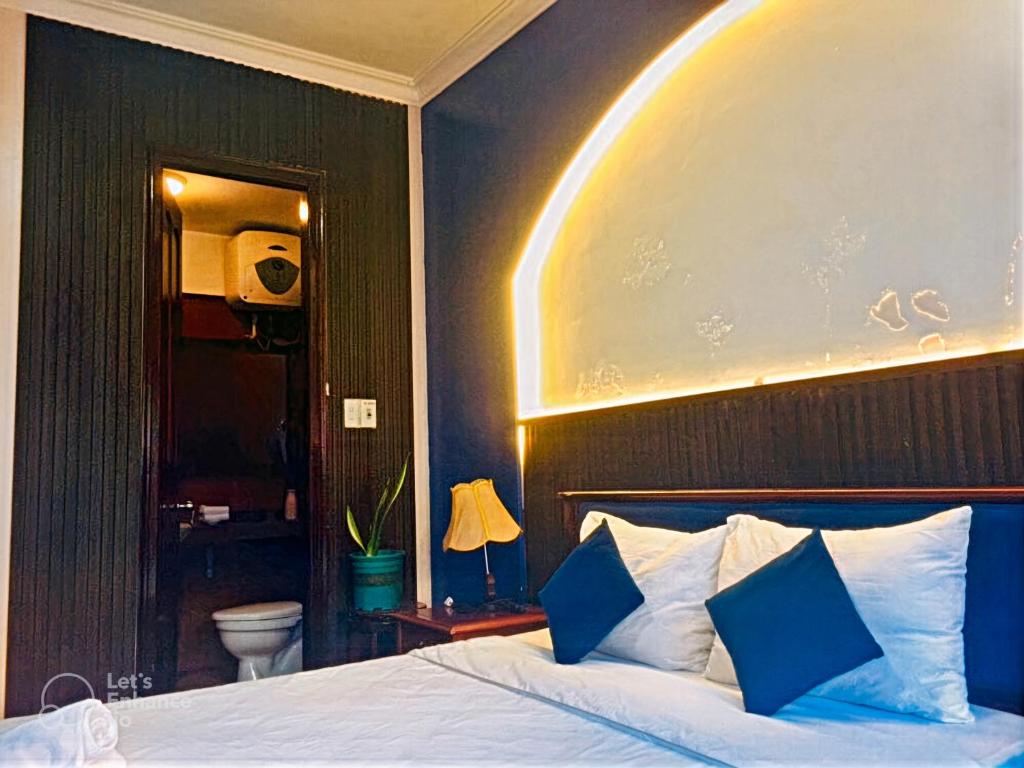 a bedroom with a large bed with blue pillows at Hue Pink Lotus Hotel in Hue