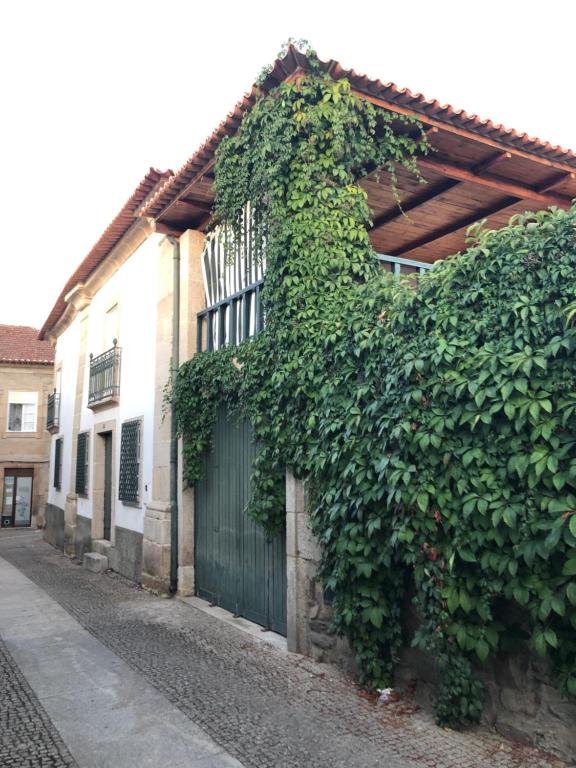 un edificio cubierto de hiedra con una puerta y una valla en Esquina do Visconde, Guesthouse, en Torre de Moncorvo