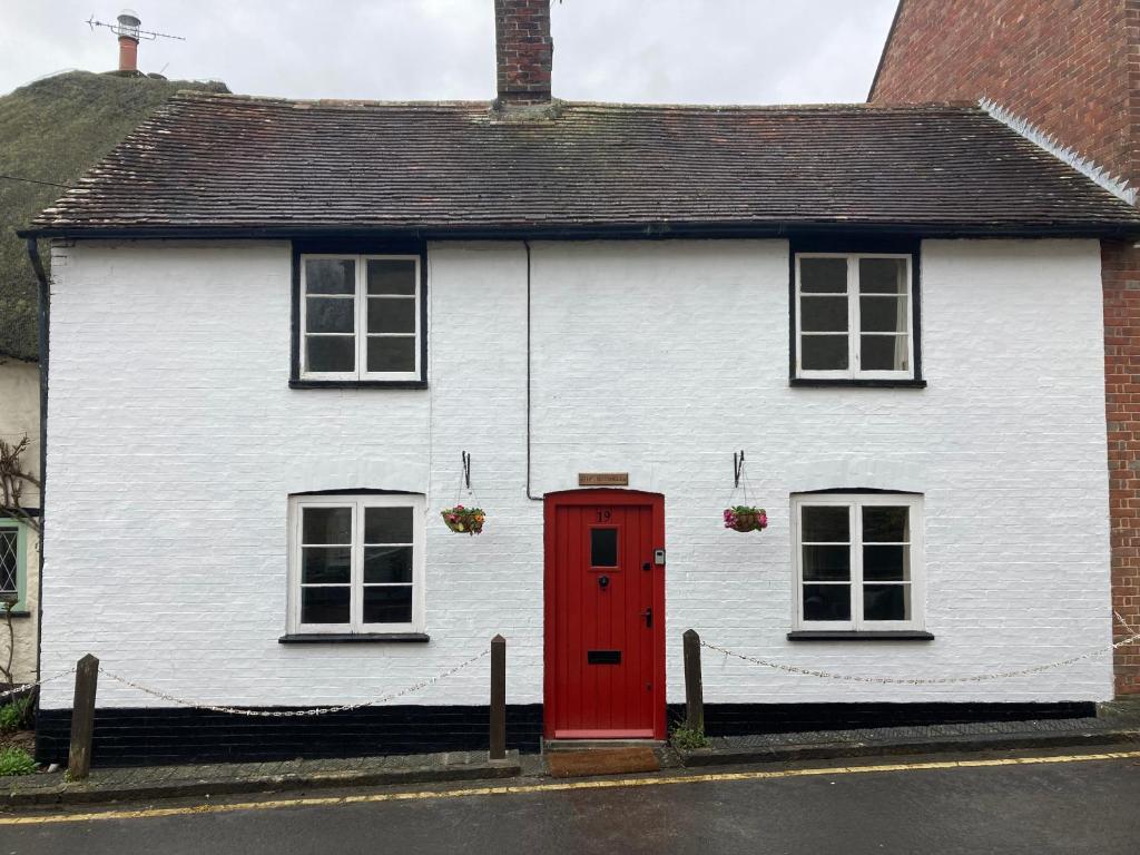 a white house with a red door and two windows at Nutshell in Sturminster Newton