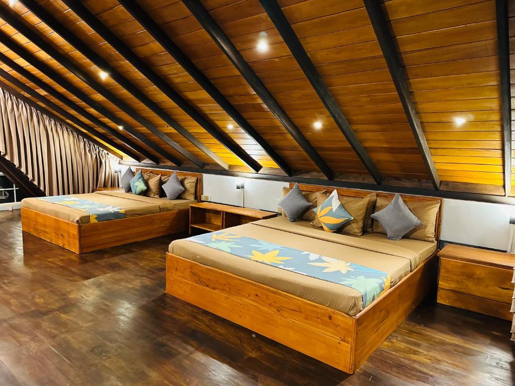 two beds in a room with wooden ceilings at Cabin 7000 feet Nuwaraeliya in Nuwara Eliya