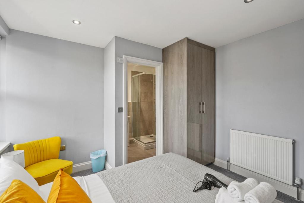 a bedroom with a bed and a yellow chair at BridgeCity Modern Holiday Condo in Maidstone - f8 in Kent