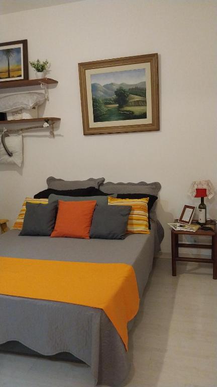1 dormitorio con 1 cama con una pintura en la pared en Apartamento aconchegante em Petrópolis, en Petrópolis