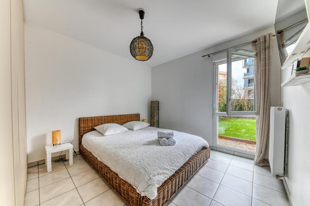 um quarto com uma cama e uma grande janela em La pause côté jardin em Décines-Charpieu