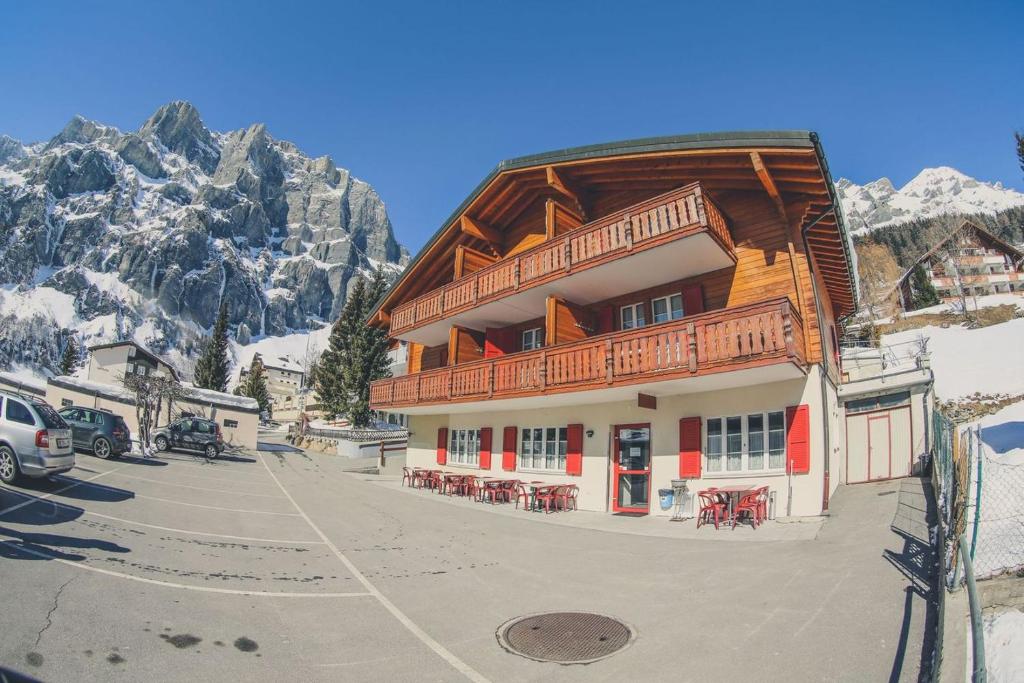 ein großes Holzgebäude mit Tischen und Stühlen vor einem Berg in der Unterkunft Touristenheim Bergfreude in Leukerbad