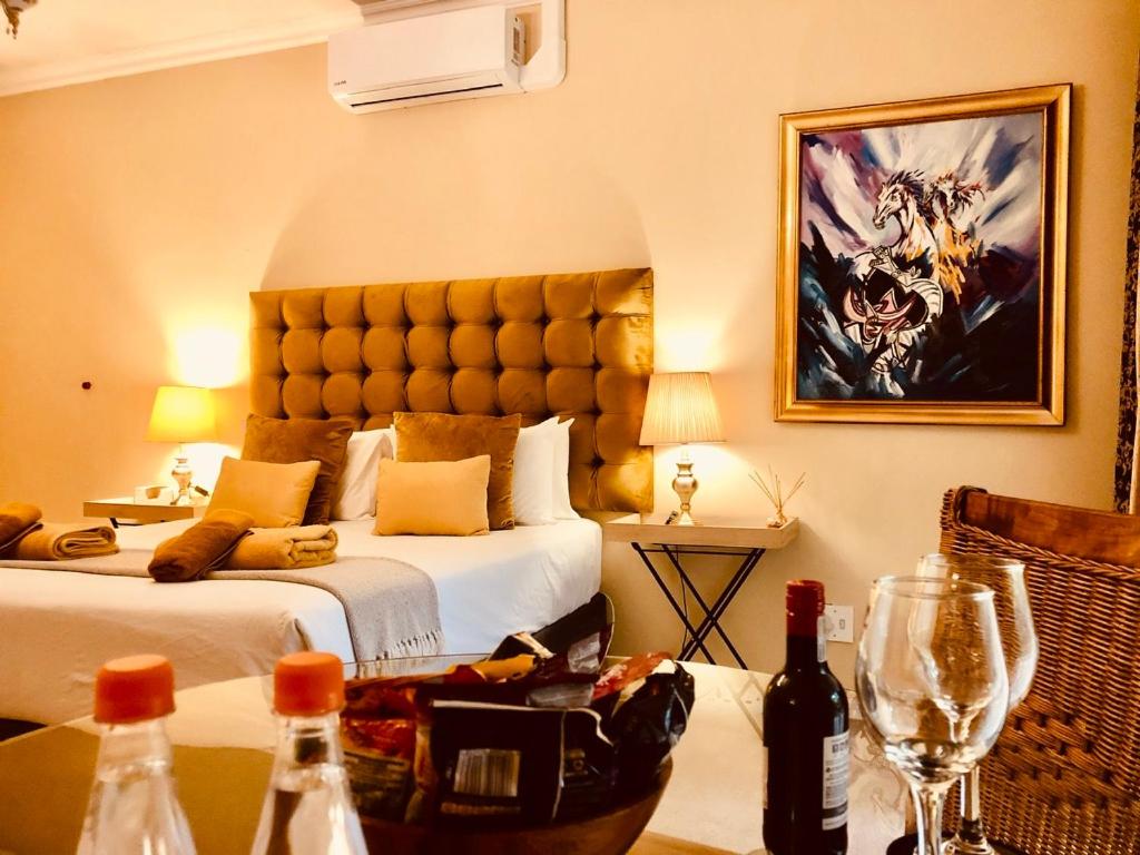 Habitación de hotel con cama y mesa con botellas de vino en 27A on Angus, en Johannesburgo