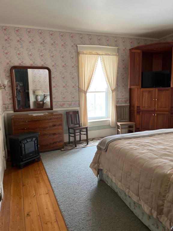 um quarto com uma cama, uma cómoda e um espelho em Antique Mansion B & B em Rutland