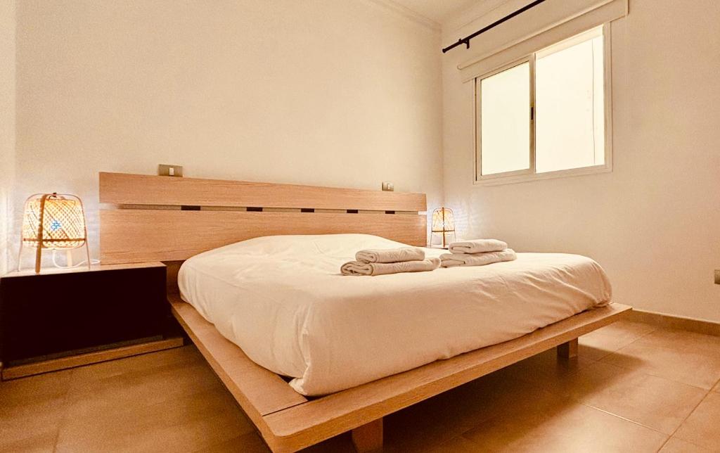 Schlafzimmer mit einem Bett mit einem Kopfteil aus Holz und einem Fenster in der Unterkunft Click & Guest - Urban and Quiet House in Vecindario