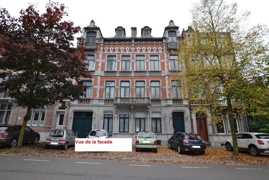 un grand bâtiment en briques avec un panneau devant lui dans l'établissement Duplex sympa Verviers, à Verviers