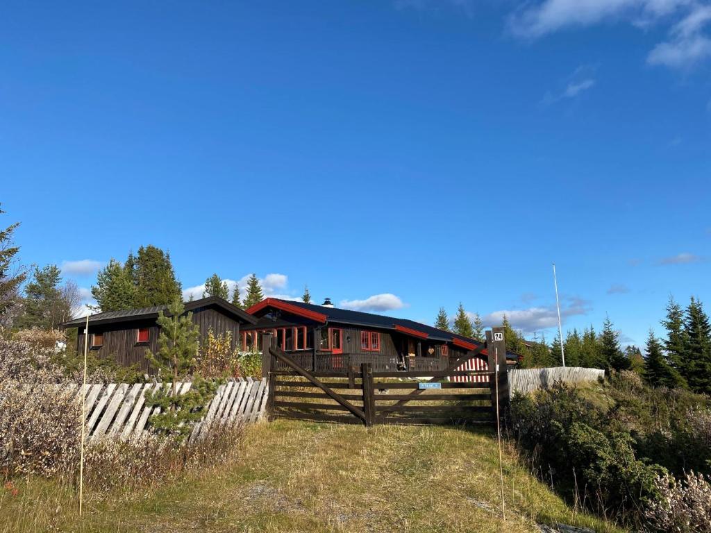 ein Holzhaus mit einem Zaun davor in der Unterkunft Kimsbu - cozy mountain cabin in hiking area in Nes i Ådal