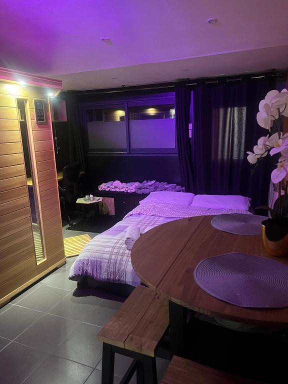 1 dormitorio con cama y mesa con luces moradas en Suite avec Sauna 36m², en Niort