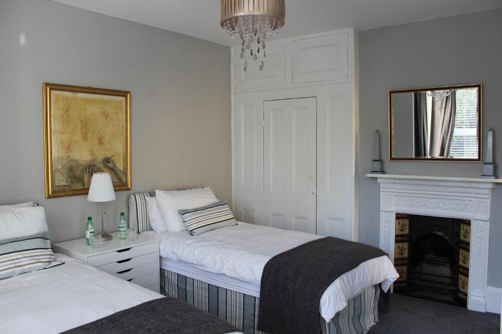 a white bedroom with two beds and a fireplace at Botleigh Villa in Rochester