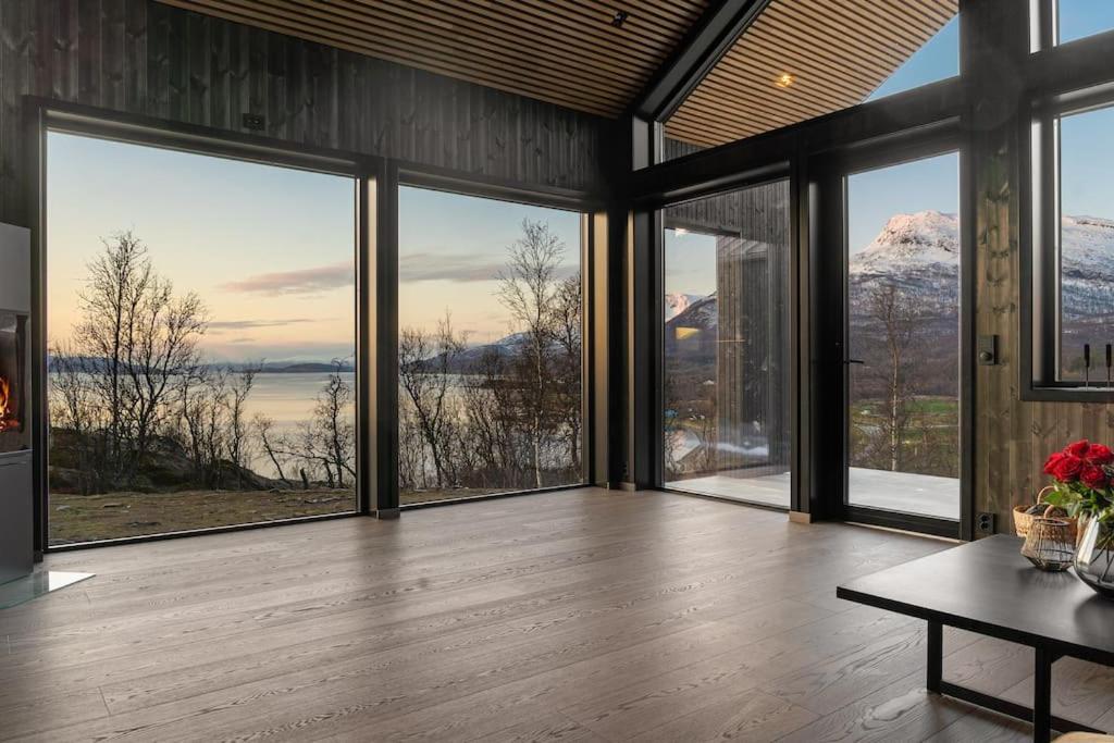 a living room with large windows and a table at Fantastisk arkitekt tegnet Snøhetta i vakker natur in Sand