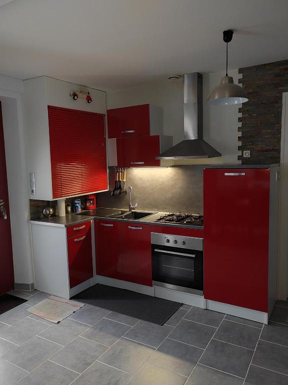 a kitchen with red cabinets and a stove at La maison des noyers in Parigné-lʼÉvêque