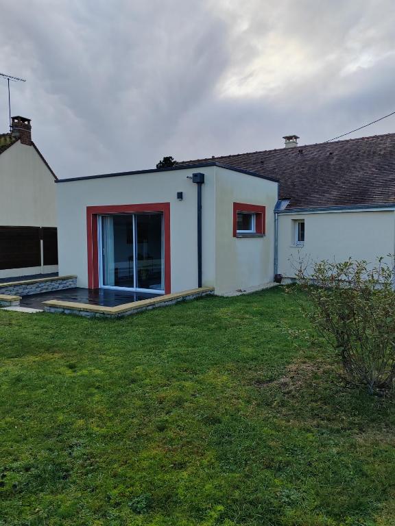 a white house with a patio and a yard at La maison des noyers in Parigné-lʼÉvêque