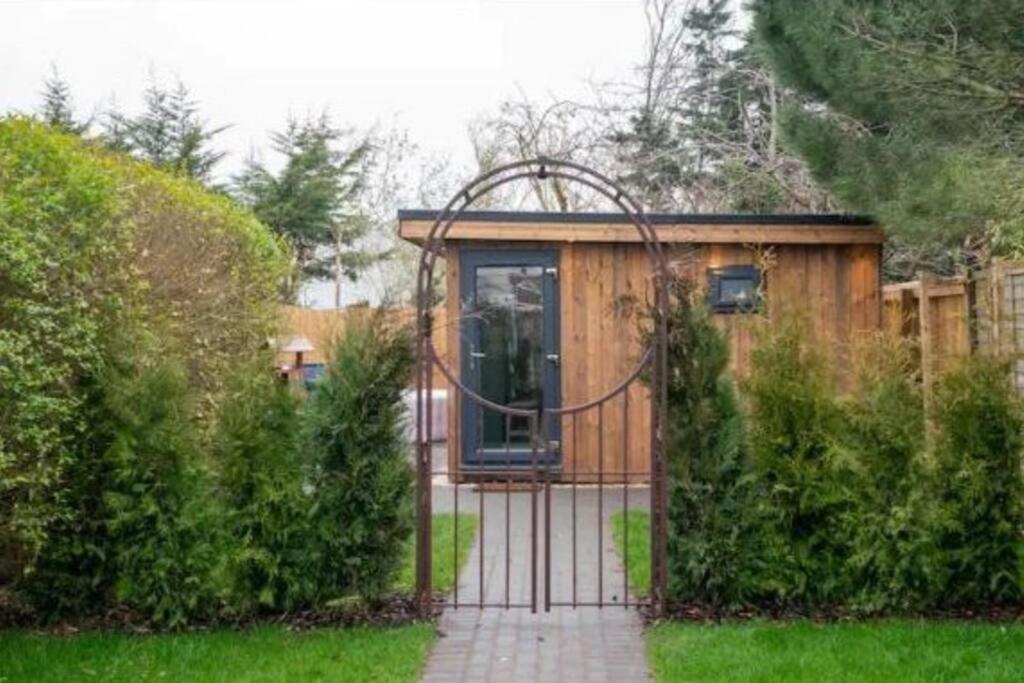 a small house with a gate in a garden at Luxury cabin with hot-tub in Cheltenham