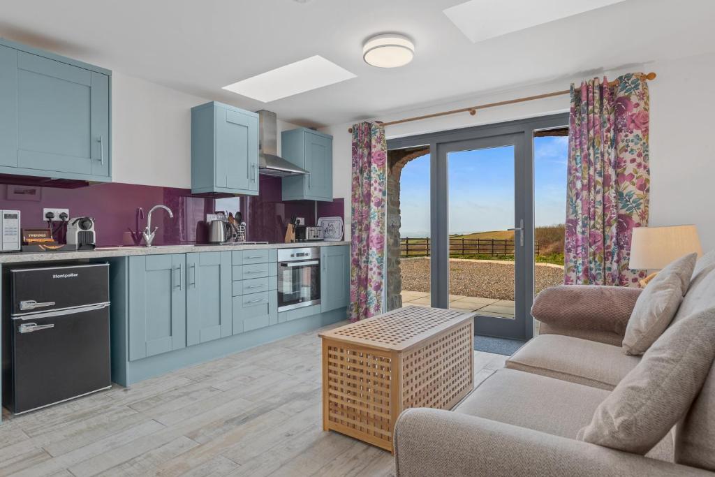 a kitchen and living room with blue cabinets at Ramsey Sea View Cottage - Dog Friendly in Pembrokeshire
