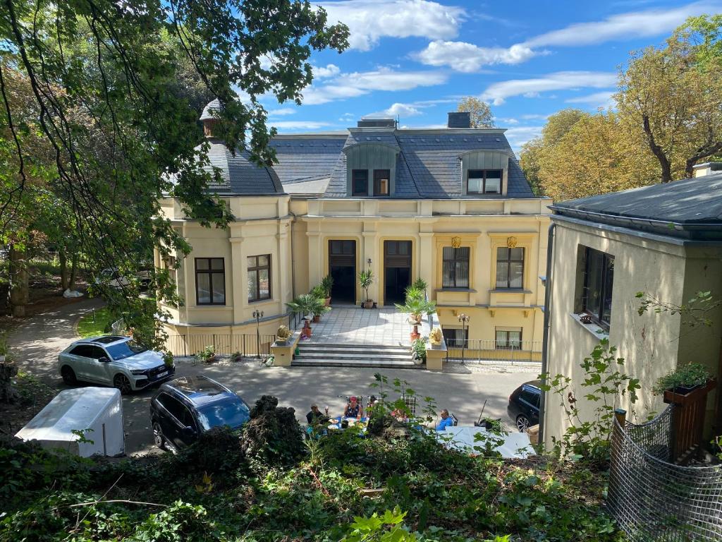 una gran casa amarilla con coches estacionados frente a ella en Villa Hirsch en Gera