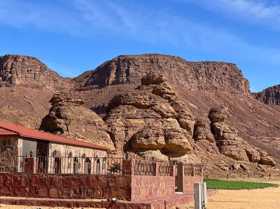 a building in front of a rocky mountain at Red Mountain Farm in AlUla