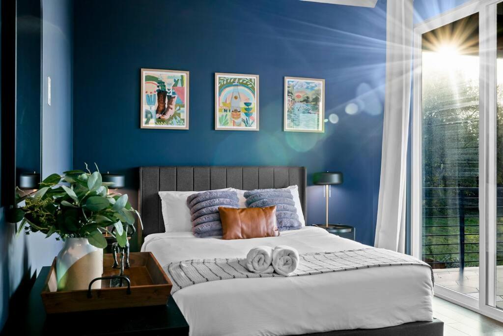 um quarto com paredes azuis e uma cama com toalhas em Downtown Gateway: Stylish Nest Near Austin Airport em Austin