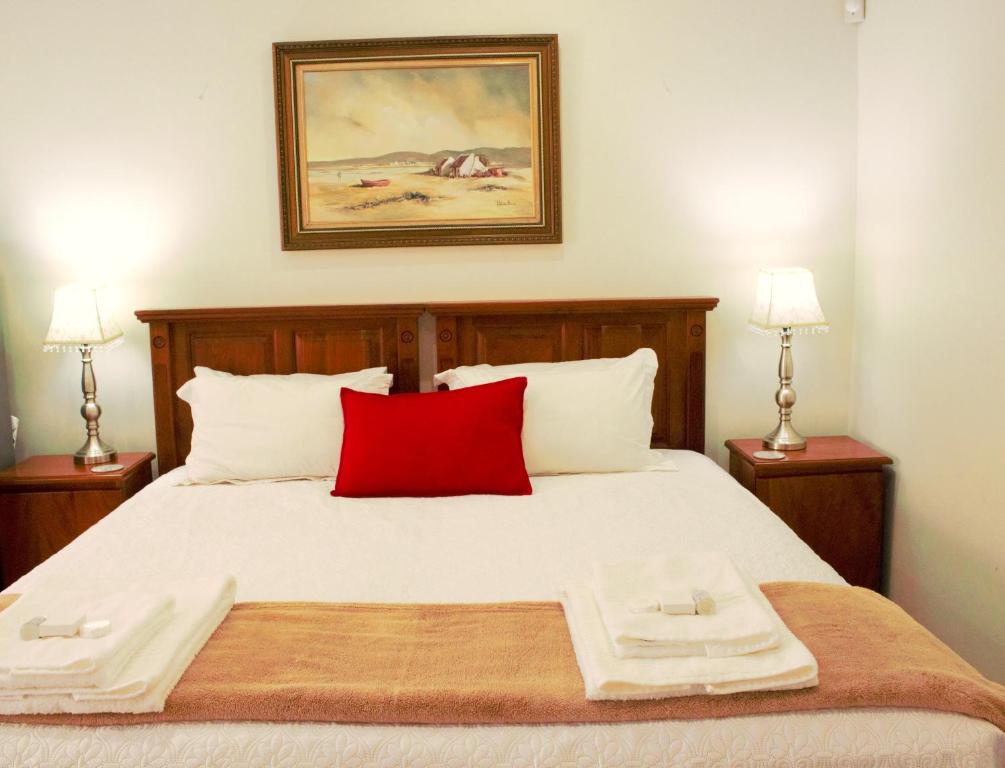 Accommodation at Potch Guesthouse في بوتشيفستروم: غرفة نوم بسرير كبير ومخدة حمراء