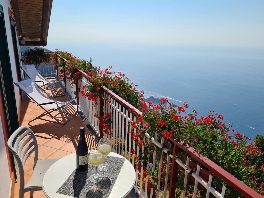 a table with wine glasses on a balcony with flowers at Villa il Dolce Tramonto in Furore