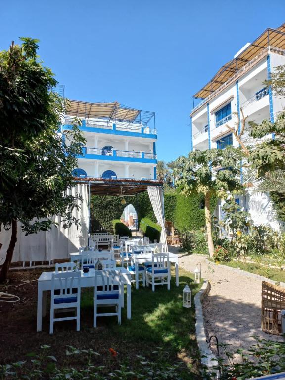 a group of white tables and chairs in front of a building at Villa Kaslan Apartments in Luxor