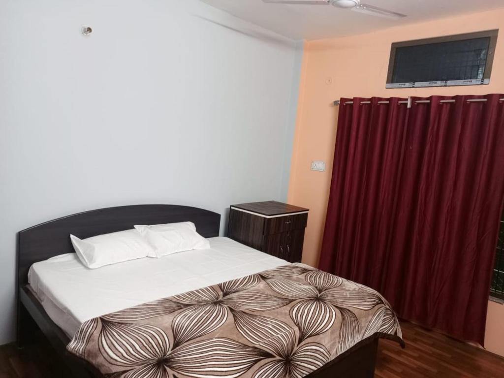 1 dormitorio con cama y cortina roja en Shri Niwas Homestay en Ayodhya