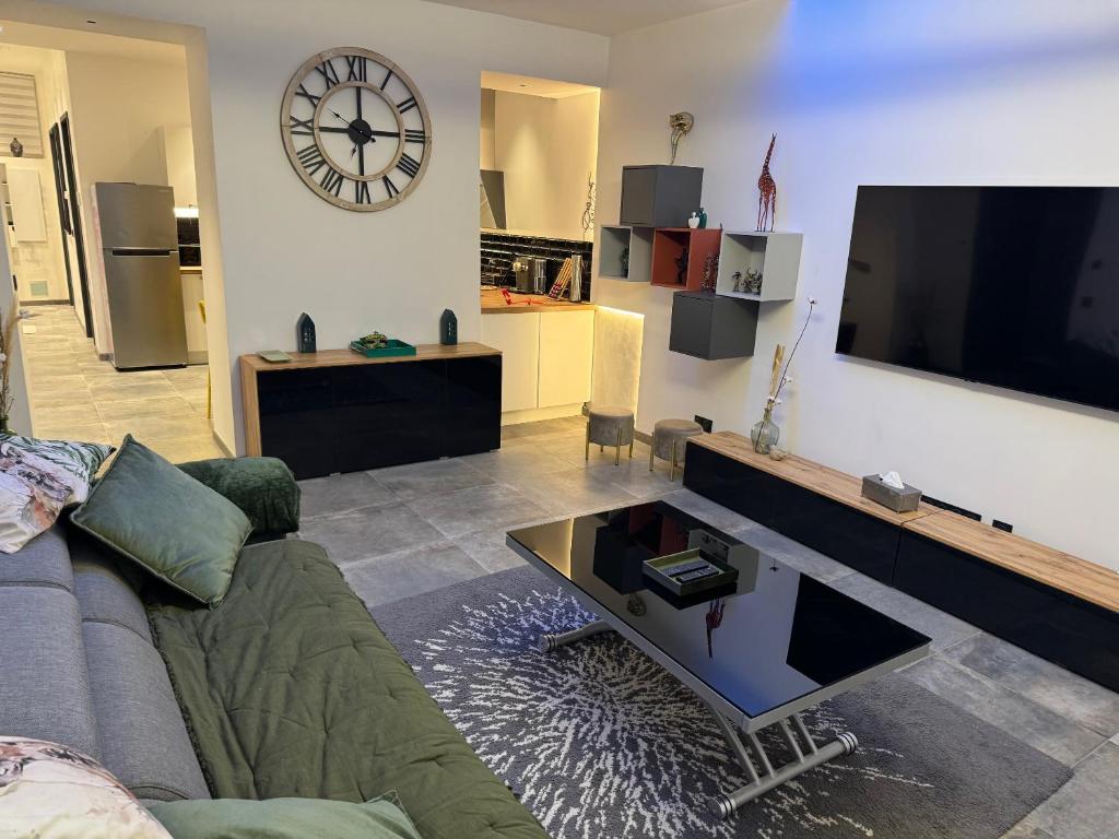 un salon avec un canapé et une horloge au mur dans l'établissement PitchMoon Bel Appartement 85 m2, grande terrasse extérieure, à Grasse