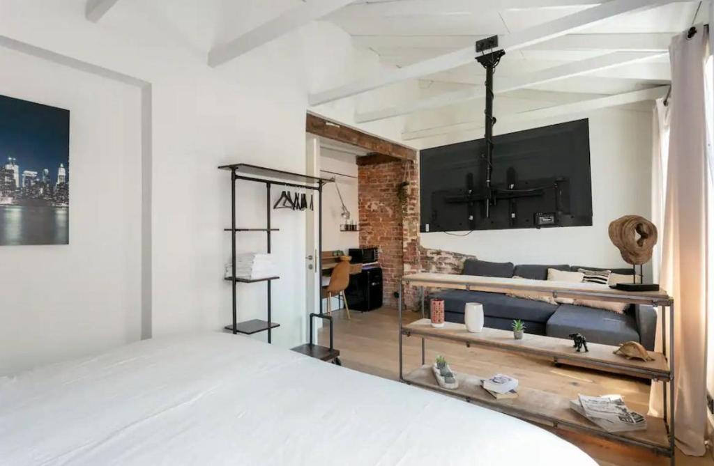 um quarto com uma cama e uma televisão na parede em Good Vibe Rooms em Bilbao