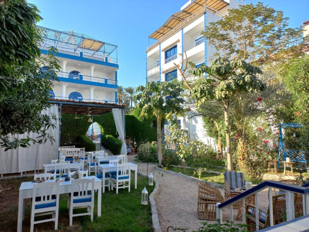 a patio with white tables and chairs in front of a building at Villa Kaslan Apartments in Luxor