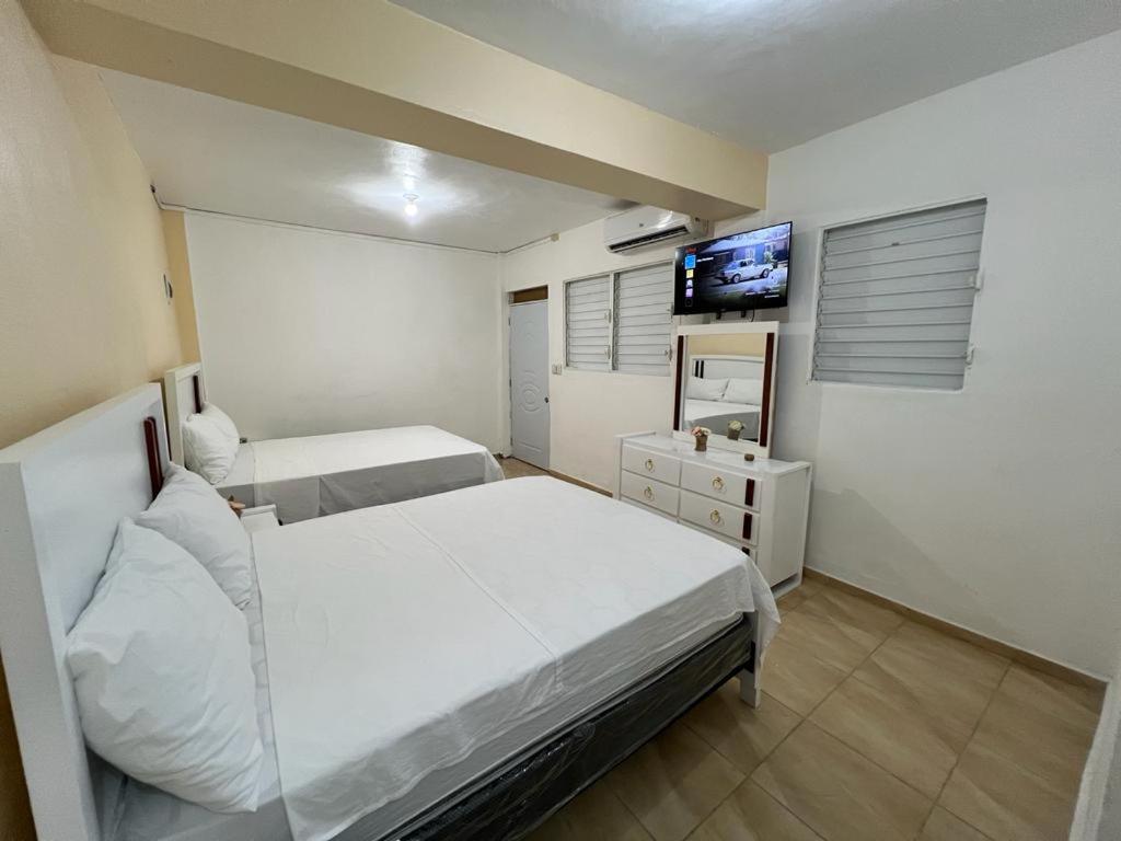 a bedroom with two beds and a flat screen tv at Habitación doble Villa Marchena Azua in Azua de Compostela