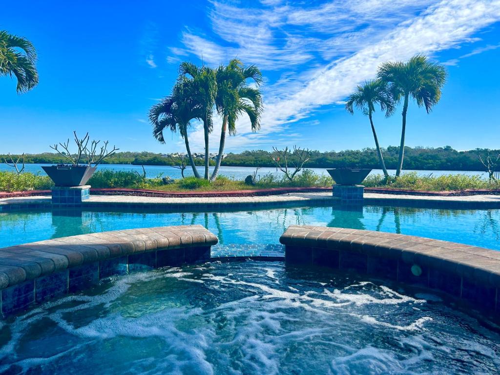 una piscina con palmeras y un cuerpo de agua en Guest suite - Waterfront -Pool & Hot tub- Walk to Beach en Clearwater Beach