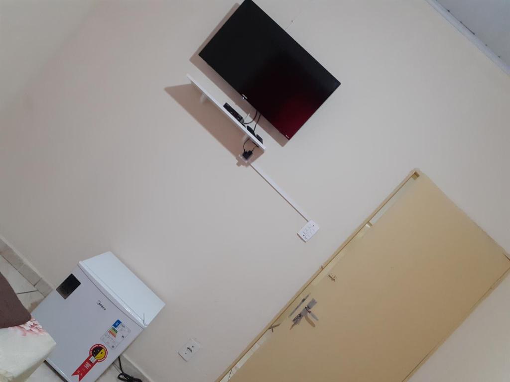 a kitchen with a refrigerator and a tv on a wall at Espaço matteo in Aparecida