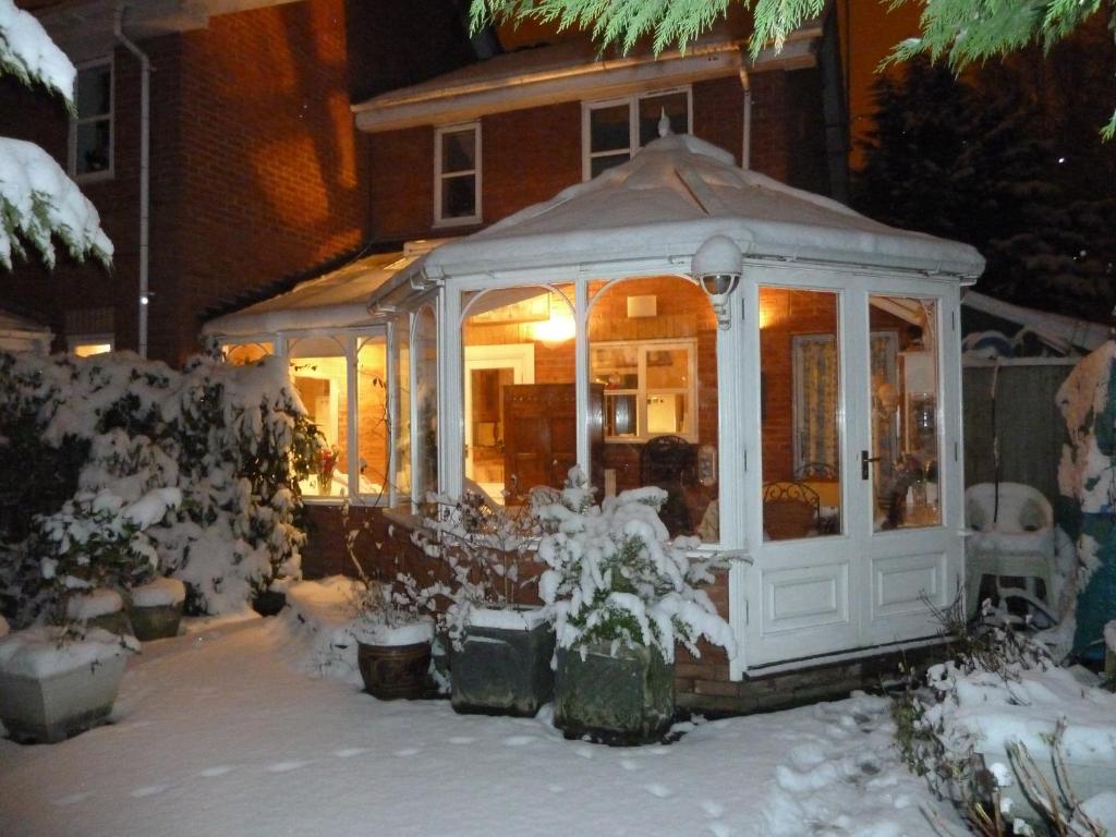 a greenhouse in the snow in front of a house at Spacious in Croxley Green