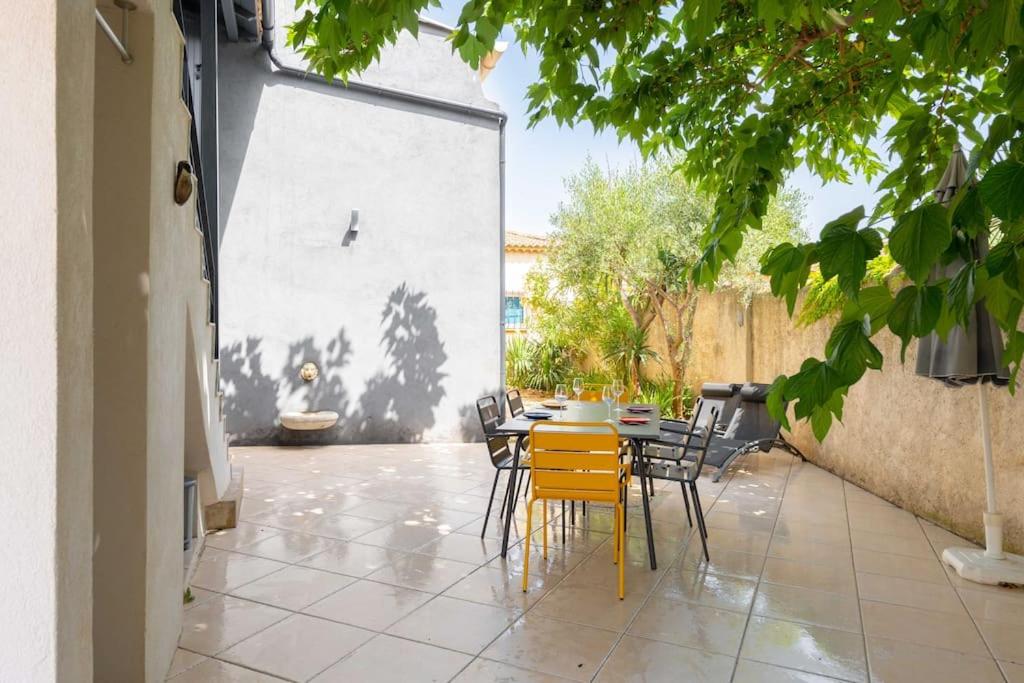 a patio with a table and chairs in a courtyard at Maison avec jardin &quot;les Néréïdes&quot; port et plage de la Pointe Rouge Marseille in Marseille