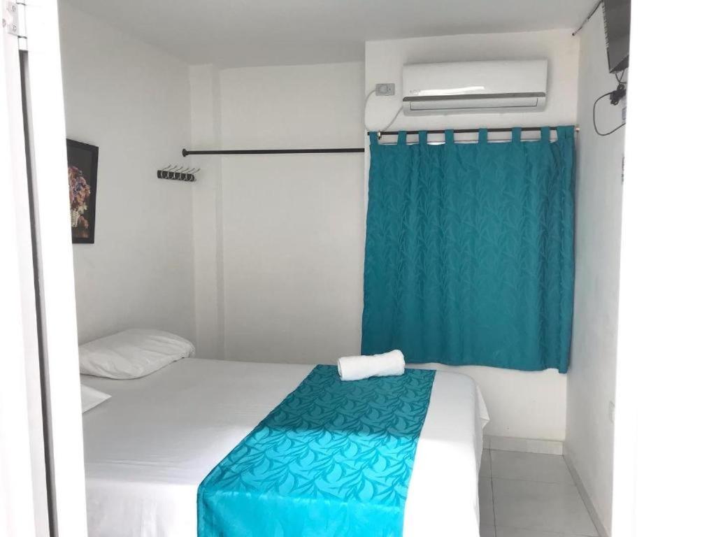 a small room with a bed and a blue curtain at Hotel URUMITA MAGICA in Valledupar