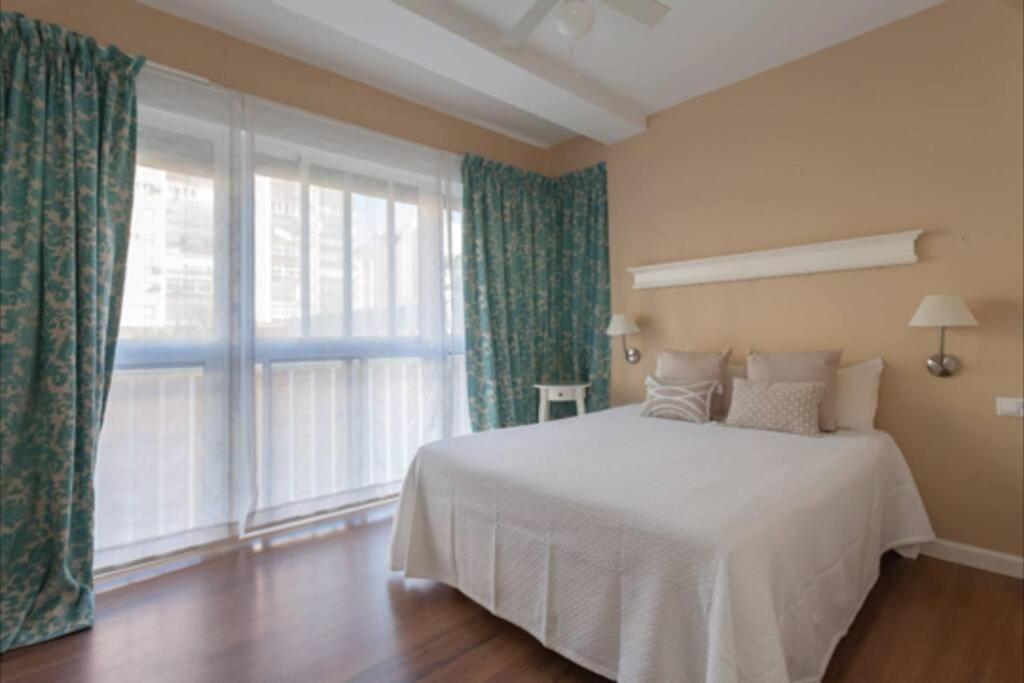 una camera con un letto bianco e una grande finestra di Plaza Madrid Ha Apartment a Cadice