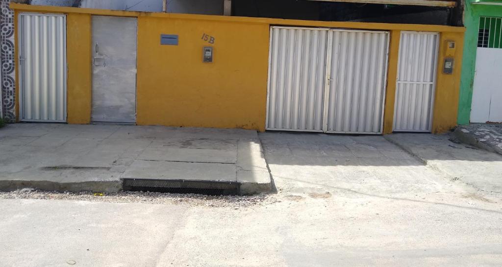 un bâtiment jaune avec des portes blanches dans une rue dans l'établissement Hospede-se no IPSEP , em Recife , próximo ao Aeroporto Internacional dos Guararapes, à Récife