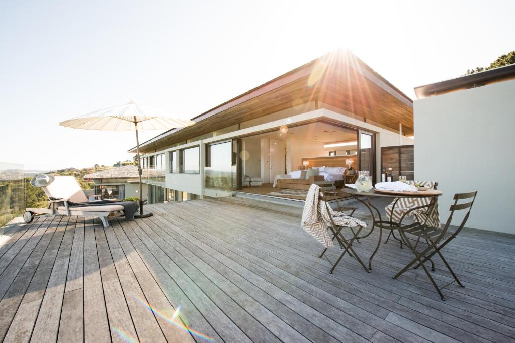 una casa con una terrazza con sedie e ombrellone di Collection Luxury Accomodation Simola House a Knysna