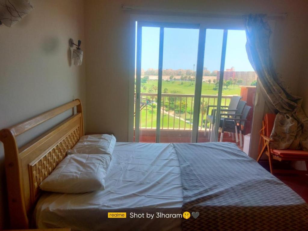 um quarto com uma cama e vista para uma varanda em Golf Porto Marina em El Alamein