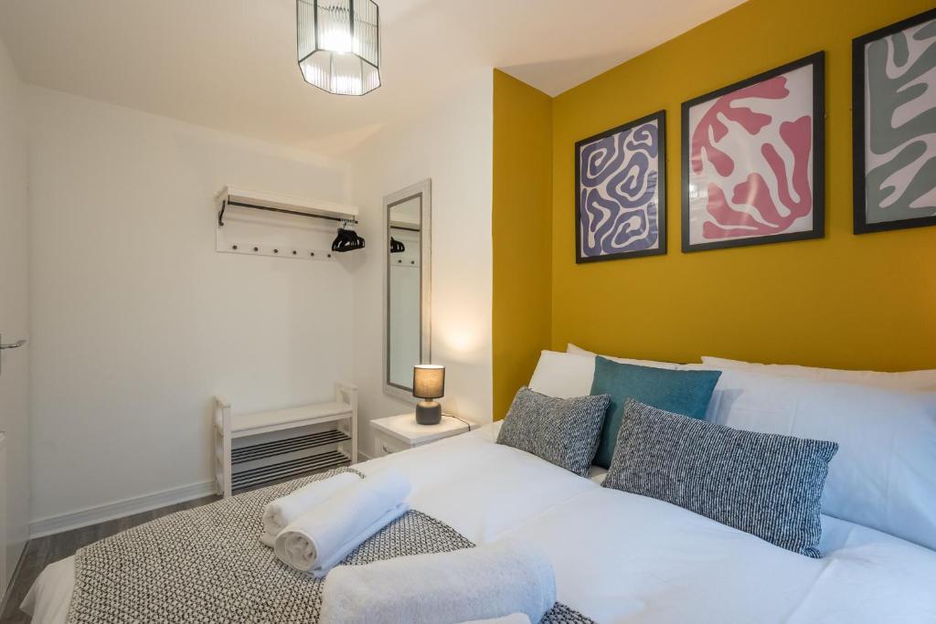 ein Schlafzimmer mit einem weißen Bett und einer gelben Wand in der Unterkunft Belfast City Centre + Parking by StayByNumbers. in Belfast