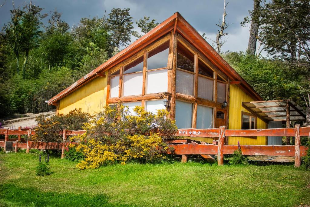 una casa amarilla con una valla delante de ella en Cabañas Posada de las Flores en Tolhuin