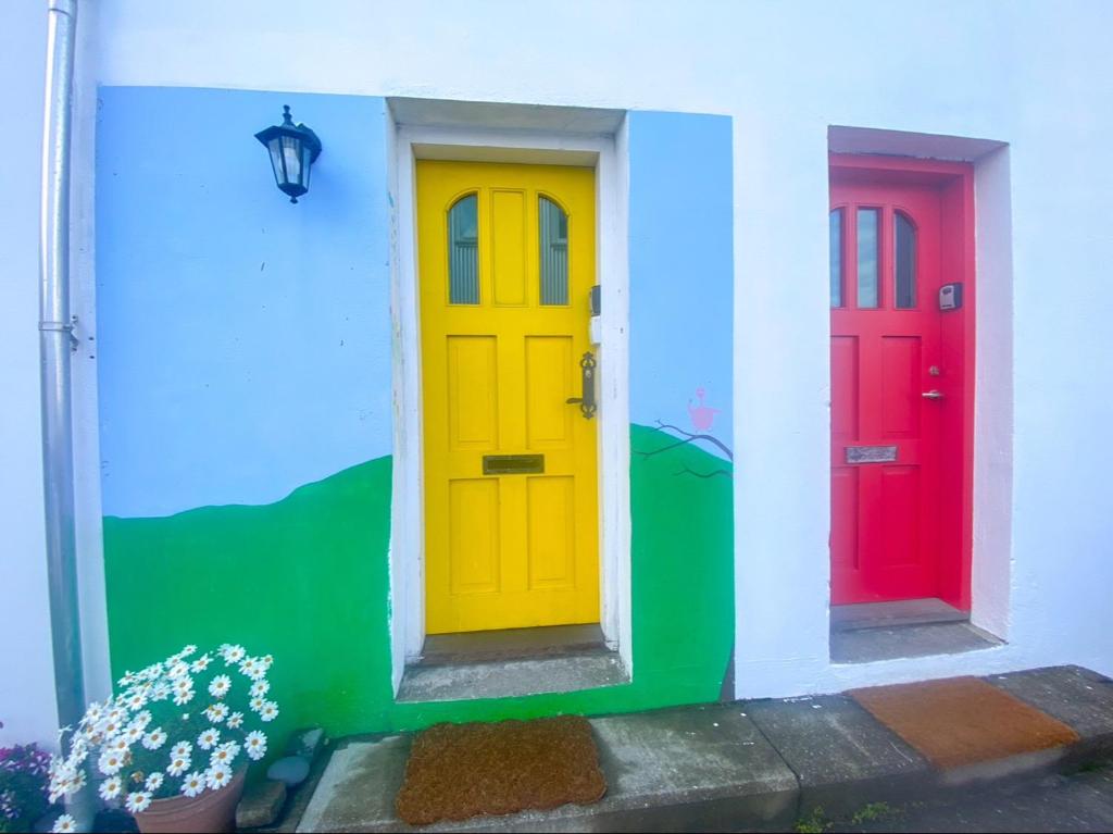 three colorful doors on a house with flowers at Enjoy Reykjavík Yellow Door Apartment in Reykjavík