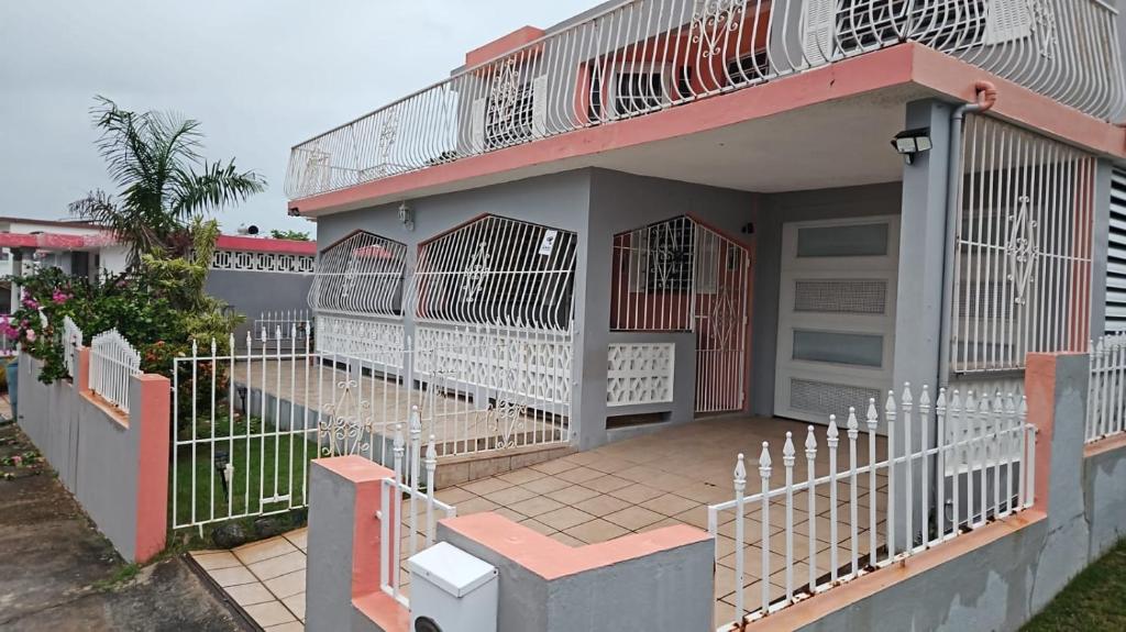 a house with a white fence and a gate at Cozy Cute Home 2nd floor in Fajardo