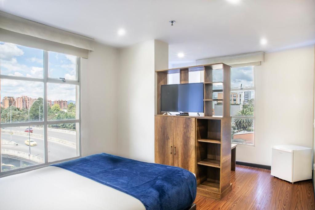 a bedroom with a bed and a flat screen tv at Hotel Black Usaquen in Bogotá