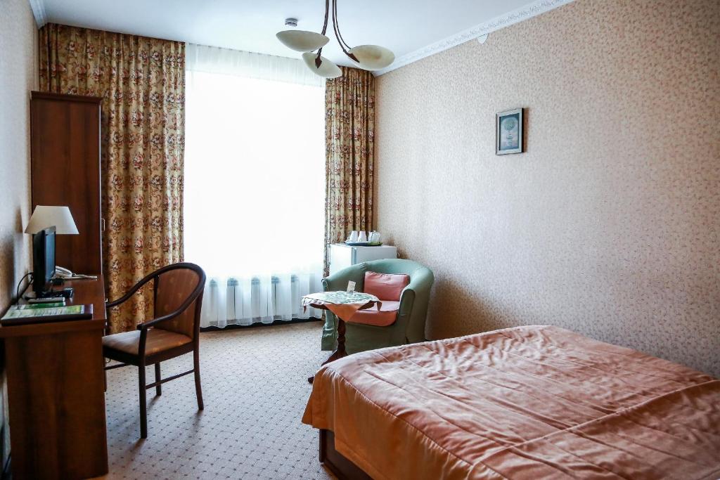 Habitación de hotel con cama, silla y escritorio. en Vizit Hotel, en Yekaterinburg