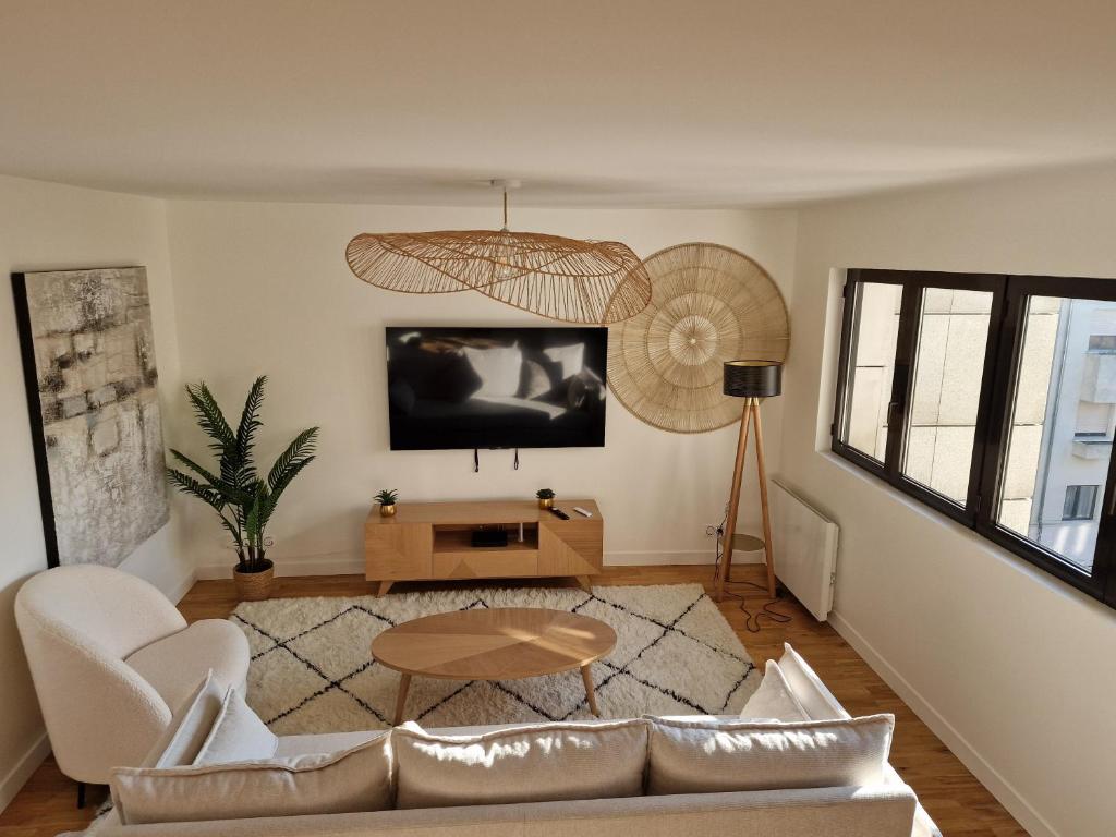 a living room with a couch and a table at Appartement Enghien-les-Bains à 7 min du Casino Barrière in Enghien-les-Bains