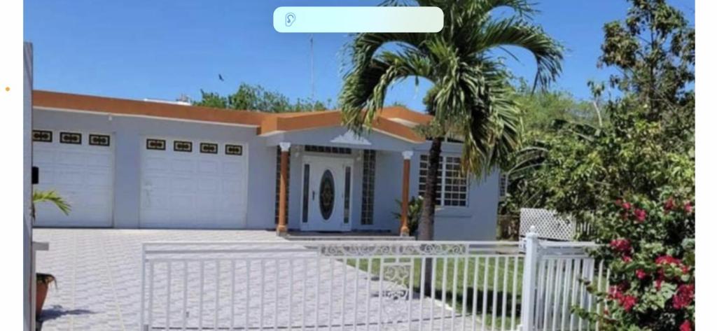 una casa con una valla blanca y una palmera en My dulce hogar, en Isabela